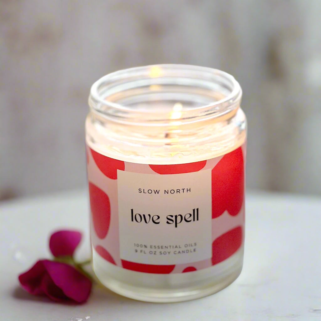 Lit Love Spell eucalyptus and lavender candle from Slow North, emitting a gentle glow, with visible rose quartz chips enhancing the non-toxic wax.