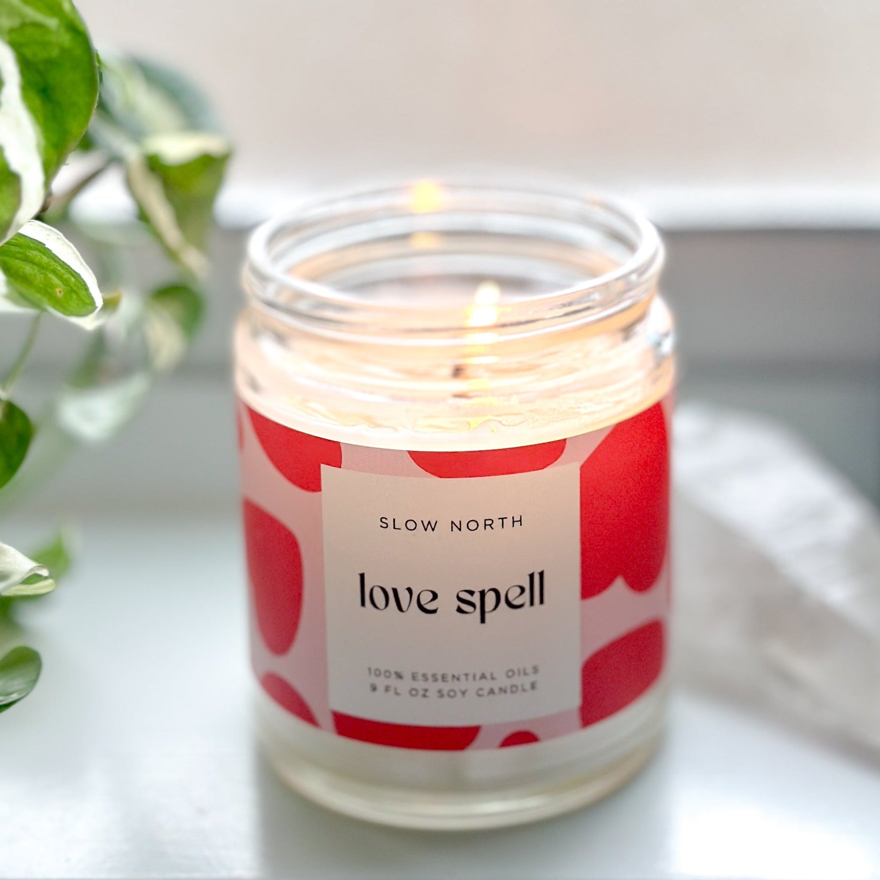 Lit Love Spell eucalyptus and lavender candle from Slow North, emitting a gentle glow, with visible rose quartz chips enhancing the non-toxic wax.