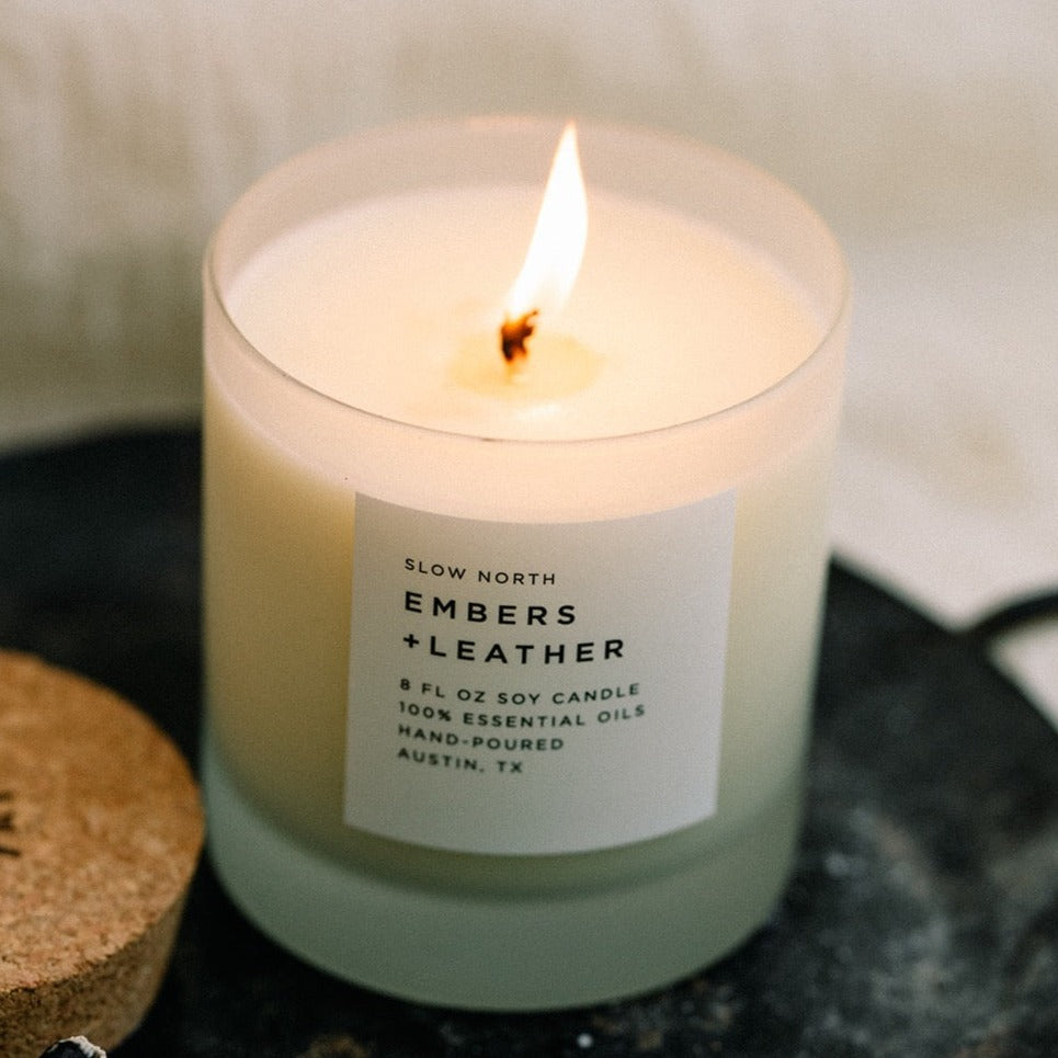 close up of lit white candle in frosted glass tumbler